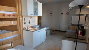 Een praktische keuken met een wastafel, een eettafeltje en een bankje.