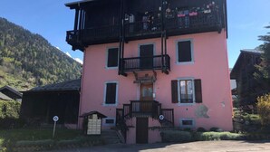 Een roze gebouw met een balkon en een bord waarop 