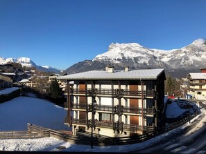 A multi-story building with balconies, a snow-covered ground, and a mountainous backdrop. - 1st floor, view mountain, tv, ski locker, 29m², Saint Gervais (Saint-Gervais-les-Bains)
