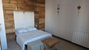 Een slaapkamer met een bed, een houten bankje en een radiator.