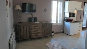 Een woonkamer met een houten kast, een flatscreen televisie, een lamp en een raam.