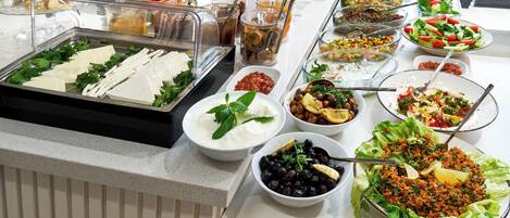 Un bufé con diferentes opciones de comida, como ensaladas, salsas y frutas.