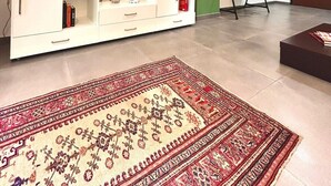 Un salon avec un meuble de rangement blanc pour les appareils électroniques, un tapis à motifs et un mur d’accent vert.