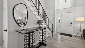 A modern staircase with black railings, a glass console table with a decorative fish sculpture, and a round mirror on the wall. - Lux Seaside Retreat Steps to Beach (Lower Township)
