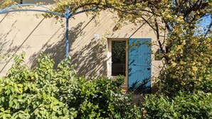 Un edificio con una porta blu, immerso nel verde e sotto un cielo azzurro.