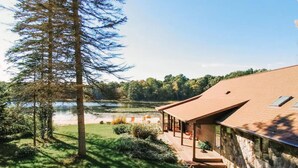 Una casa moderna con fachada de piedra, una terraza de madera y vista a un lago.