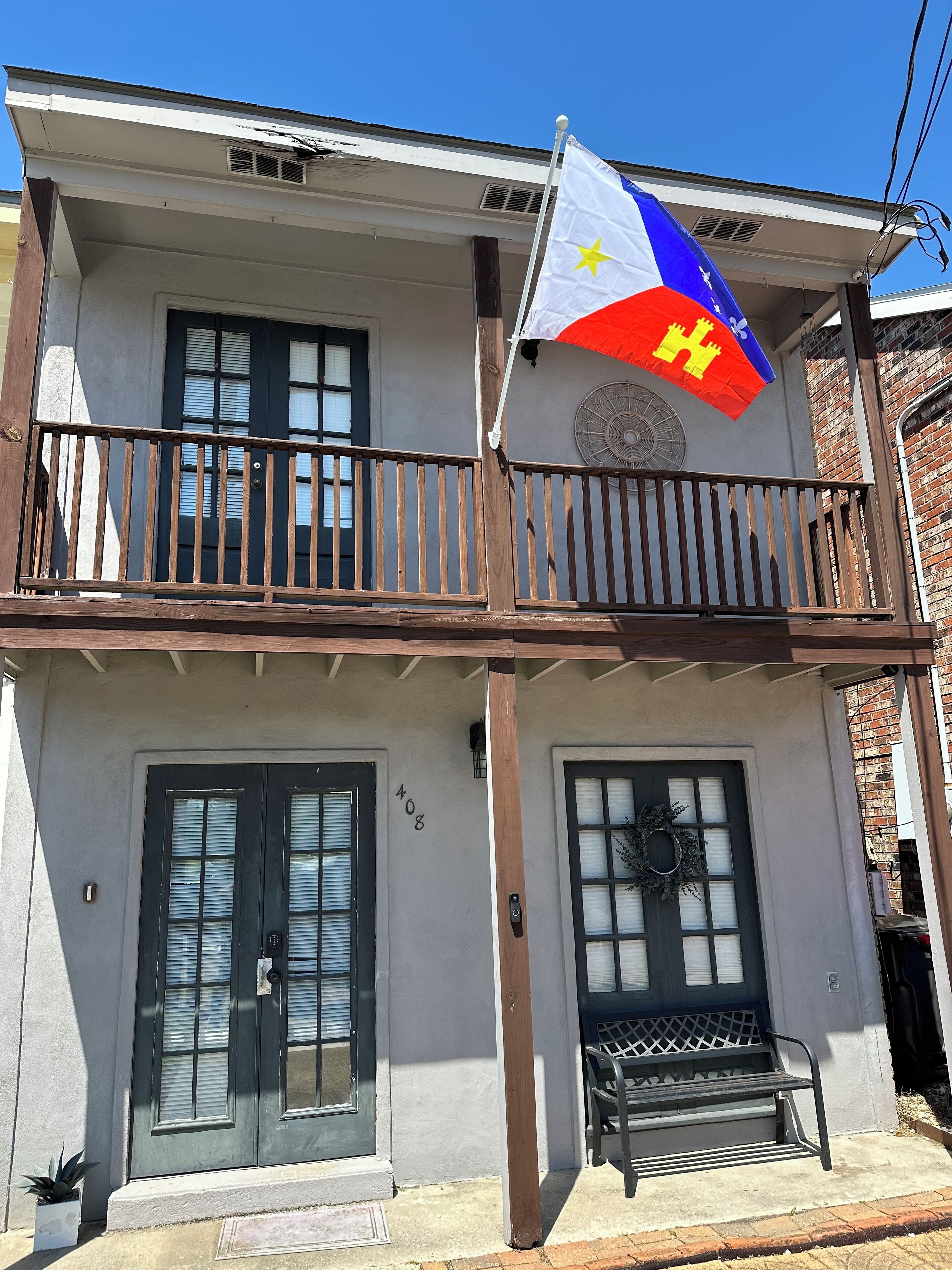 Um edifício de dois andares com varanda, uma bandeira e o número '408' na parede.