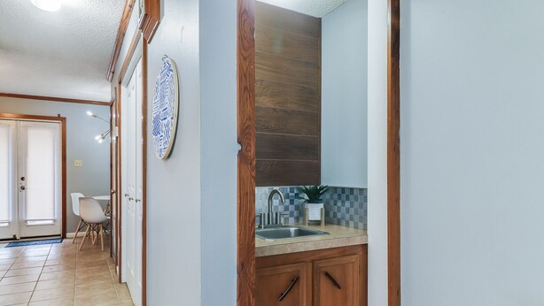 A hallway with a wooden door leading to a kitchen area with a sink and countertop. - PALM SPRINGS- 2Master Suites, Style & Location! “No chores” at checkout! (Lafayette)