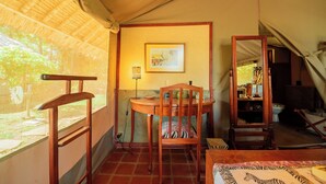 Una carpa con una silla de madera, una mesa y un cuadro en la pared.