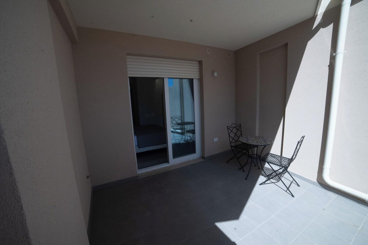 A balcony with a sliding glass door, a small table, and two chairs.