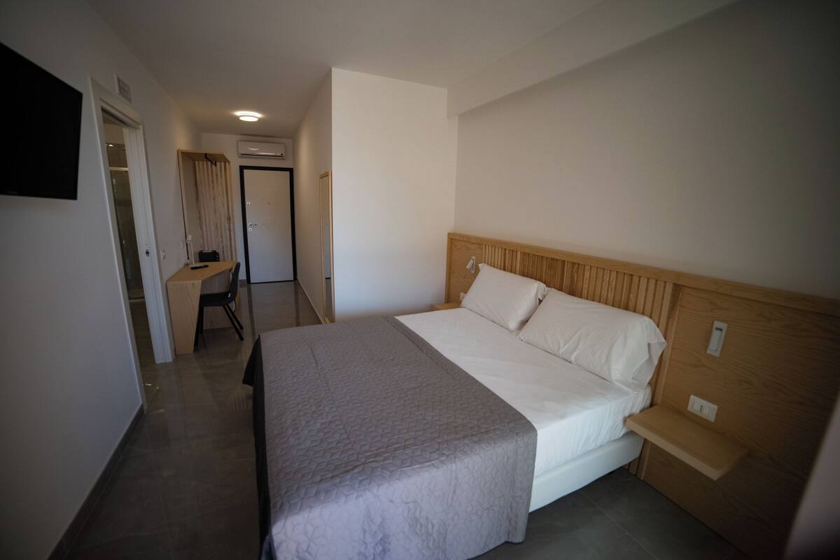 A hotel room with a bed, a desk, and a chair.
