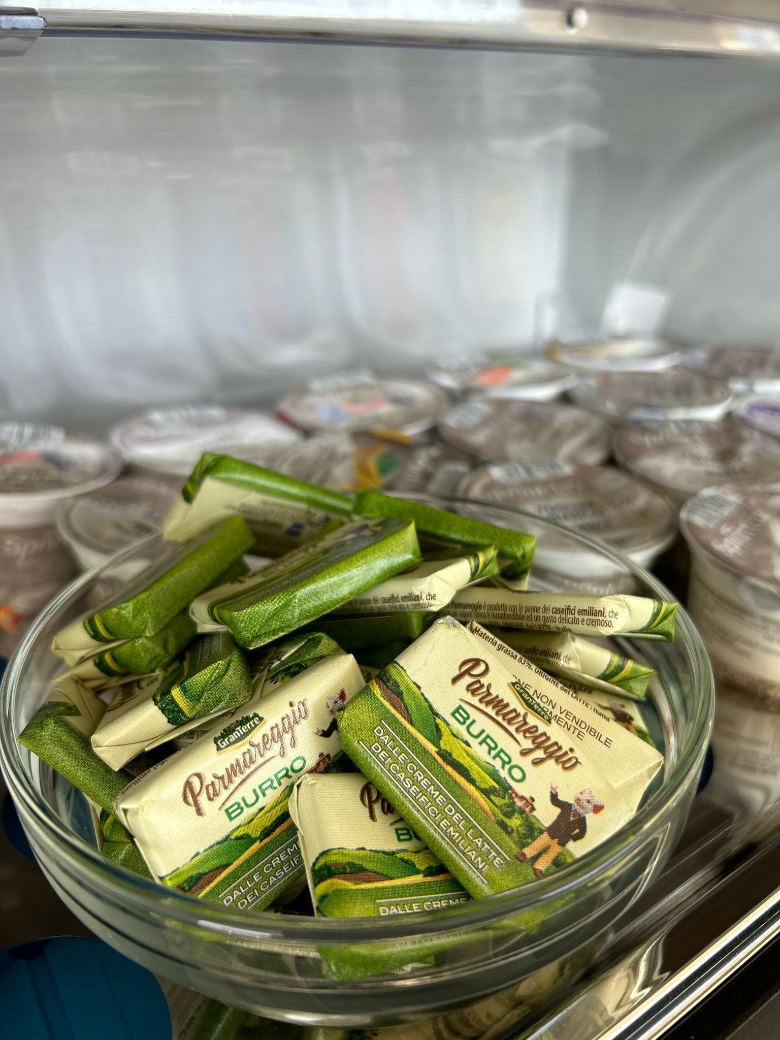 Un congelador con varios alimentos, entre ellos mantequilla envasada y verduras verdes.