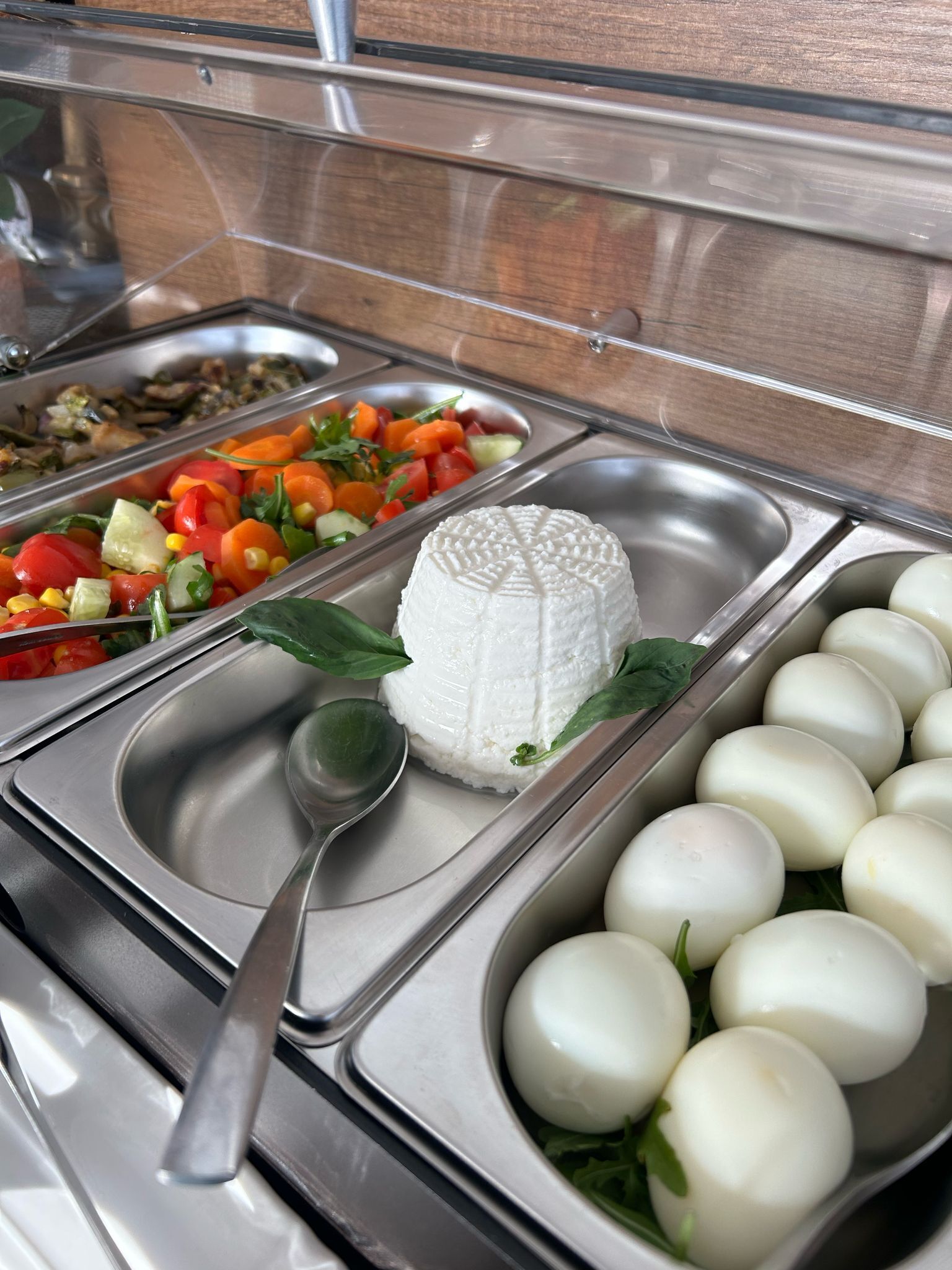 A buffet with various food options including a white cheese, a salad, and boiled eggs.