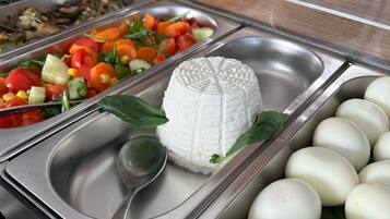 A buffet with various food options including a white cheese, a salad, and boiled eggs.