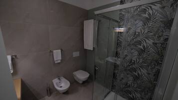 Un baño moderno con mampara de vidrio, un bidé y un inodoro.