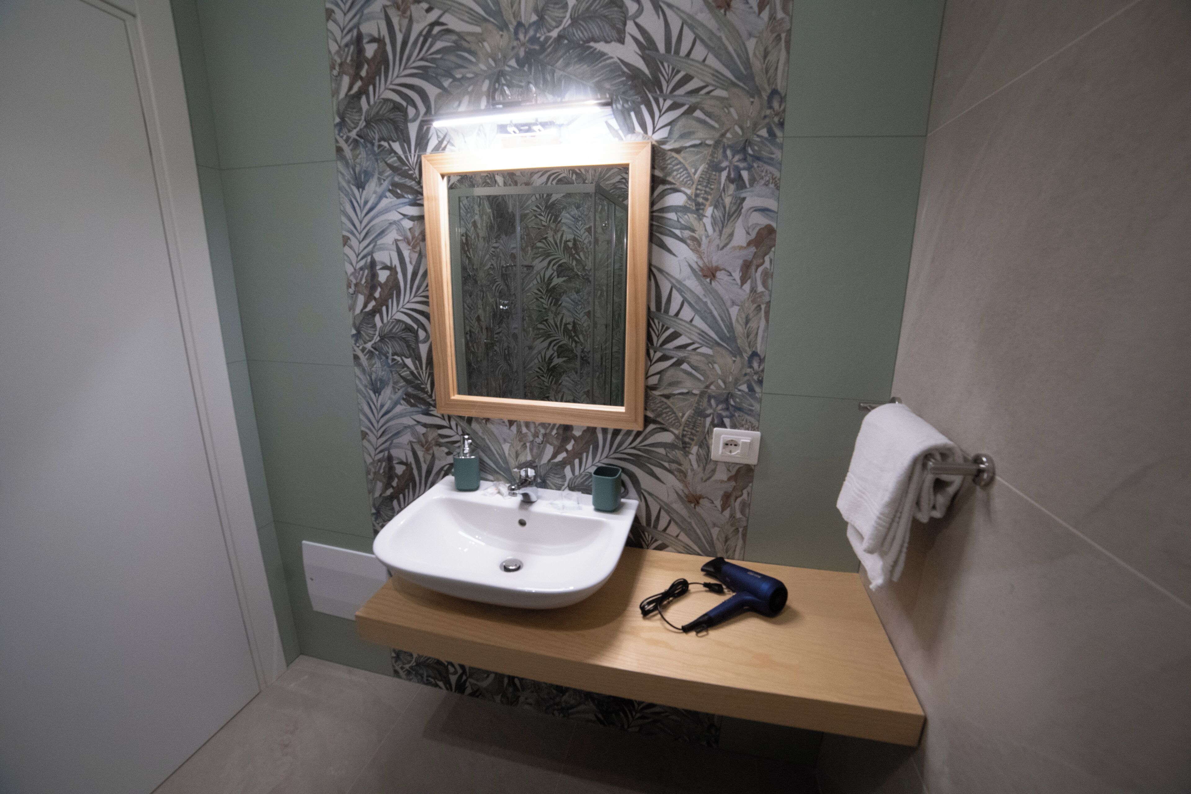 A bathroom with a white sink, a mirror, and a towel rack.