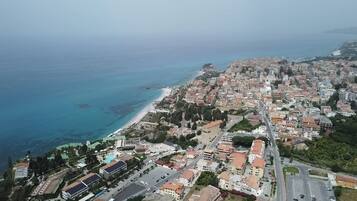 Vista aérea de un pueblo costero con playa, edificios residenciales y una carretera que lleva a la playa.