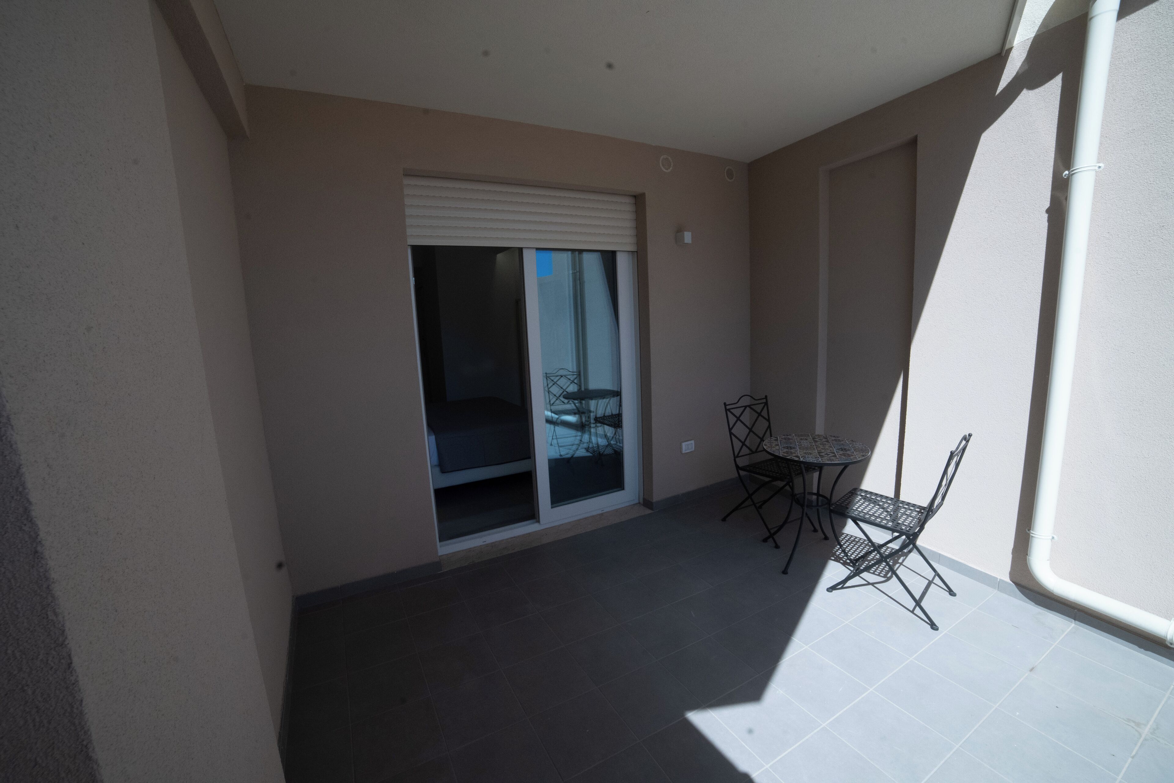 A balcony with a sliding door, a table, and two chairs.
