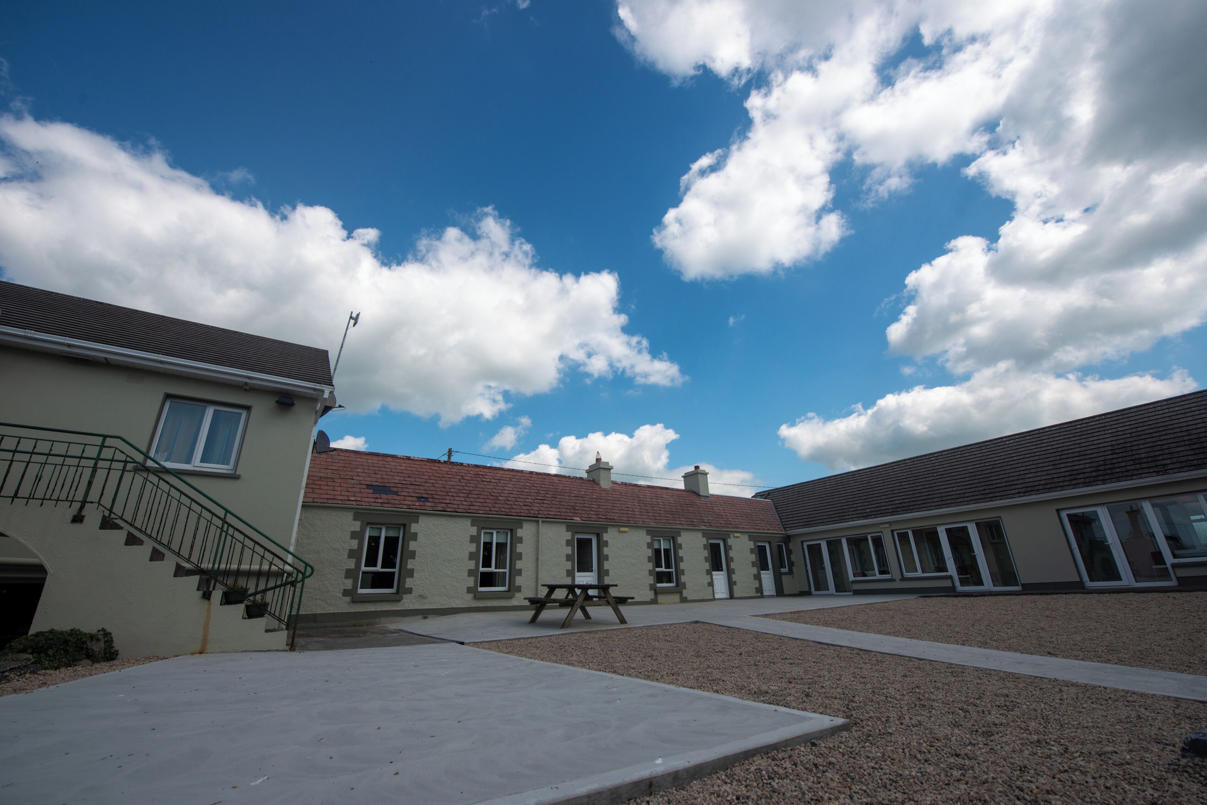 A building with a covered outdoor area, a picnic table, and a staircase leading to an entrance.