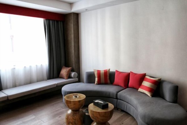 A modern living room with a grey sofa, red and beige cushions, a wooden coffee table, and a bench by the window. - Gu Er Gou Hot Spring Resort (Li County)