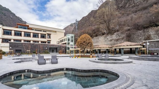 Ein Poolbereich mit Whirlpool, Liegestühlen und einem Gebäude im modernen Stil.
