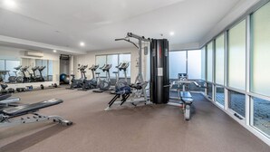 Et moderne fitnesscenter med forskellig træningsudstyr, store vinduer og udsigt over byen.