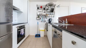 Et moderne køkken med rustfrie stålapparater, en loftmonteret grydeholder og en træbordplade.