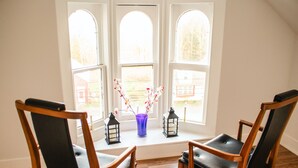A room with two wooden chairs, a blue vase with flowers, and two black lanterns on a windowsill. - Large Farmhouse near Pocono attractions! Ping-pong and Pool tables included. (South Sterling)