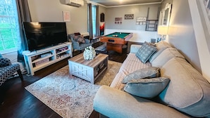 A living room with a TV, sofa, coffee table, and pool table. - Large Farmhouse near Pocono attractions! Ping-pong and Pool tables included. (South Sterling)