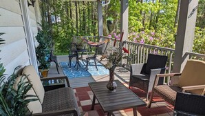 A covered outdoor patio with wicker furniture, a hammock, and potted plants. - Large Farmhouse near Pocono attractions! Ping-pong and Pool tables included. (South Sterling)