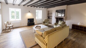 A living room with a striped sofa, a television, a fireplace, and a bookshelf. - Offrez-vous des Vacances Dans un Grand Domaine Privé Rien que Pour Vous! (Archignat)