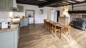 A kitchen with wooden floors, a dining table with chairs, a stove, and light-colored cabinets. - Offrez-vous des Vacances Dans un Grand Domaine Privé Rien que Pour Vous! (Archignat)