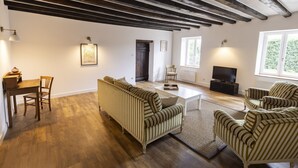 A spacious living room with a high ceiling, a fireplace, a television, and striped furniture. - Offrez-vous des Vacances Dans un Grand Domaine Privé Rien que Pour Vous! (Archignat)