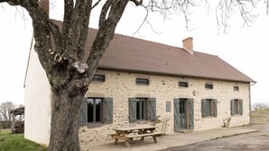 A rustic stone building with a tiled roof, a wooden bench, and a tree in front. - Offrez-vous des Vacances Dans un Grand Domaine Privé Rien que Pour Vous! (Archignat)