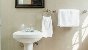 Et badeværelse med et væghængt håndvask, et spejl, en håndklædestang og et toilet.