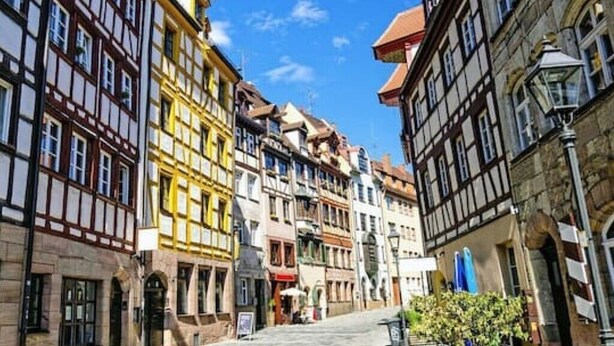 A narrow street lined with traditional half-timbered buildings, a cobblestone path, and a small tree in the foreground. - Gemütlich Zentrale Souterraint Wohnung 65qm (Nürnberg)