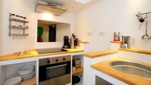 A compact kitchen with a sink, stove, and oven, wooden countertops, and a small shelf with kitchen items. - Gemütlich Zentrale Souterraint Wohnung 65qm (Nürnberg)