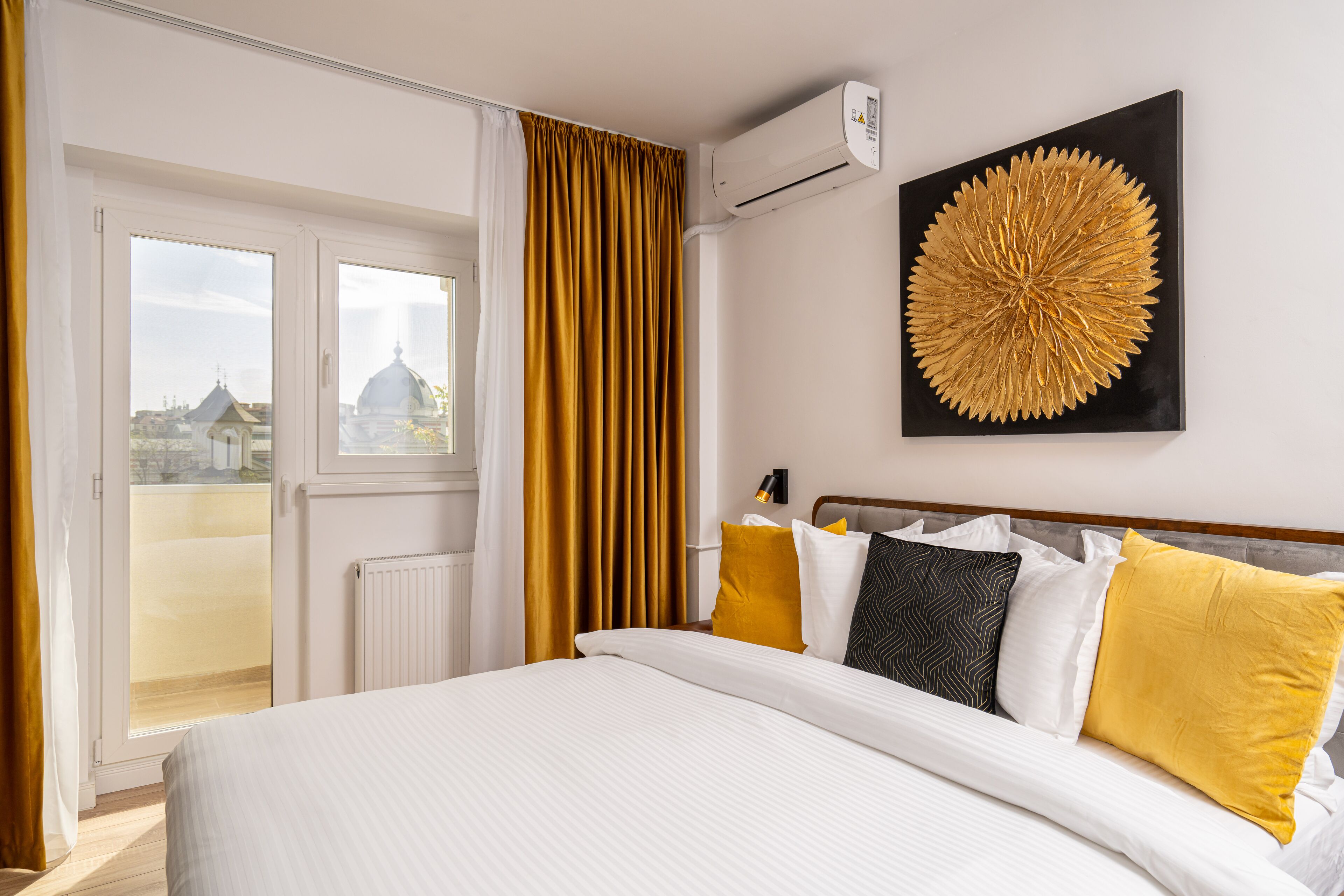 Une chambre d’hôtel avec un lit, une grande fenêtre, un radiateur et un climatiseur fixé au mur.