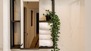 Ein Badezimmer mit Marmorwand, einem Handtuchhalter mit gefalteten Handtüchern und einer Zimmerpflanze.