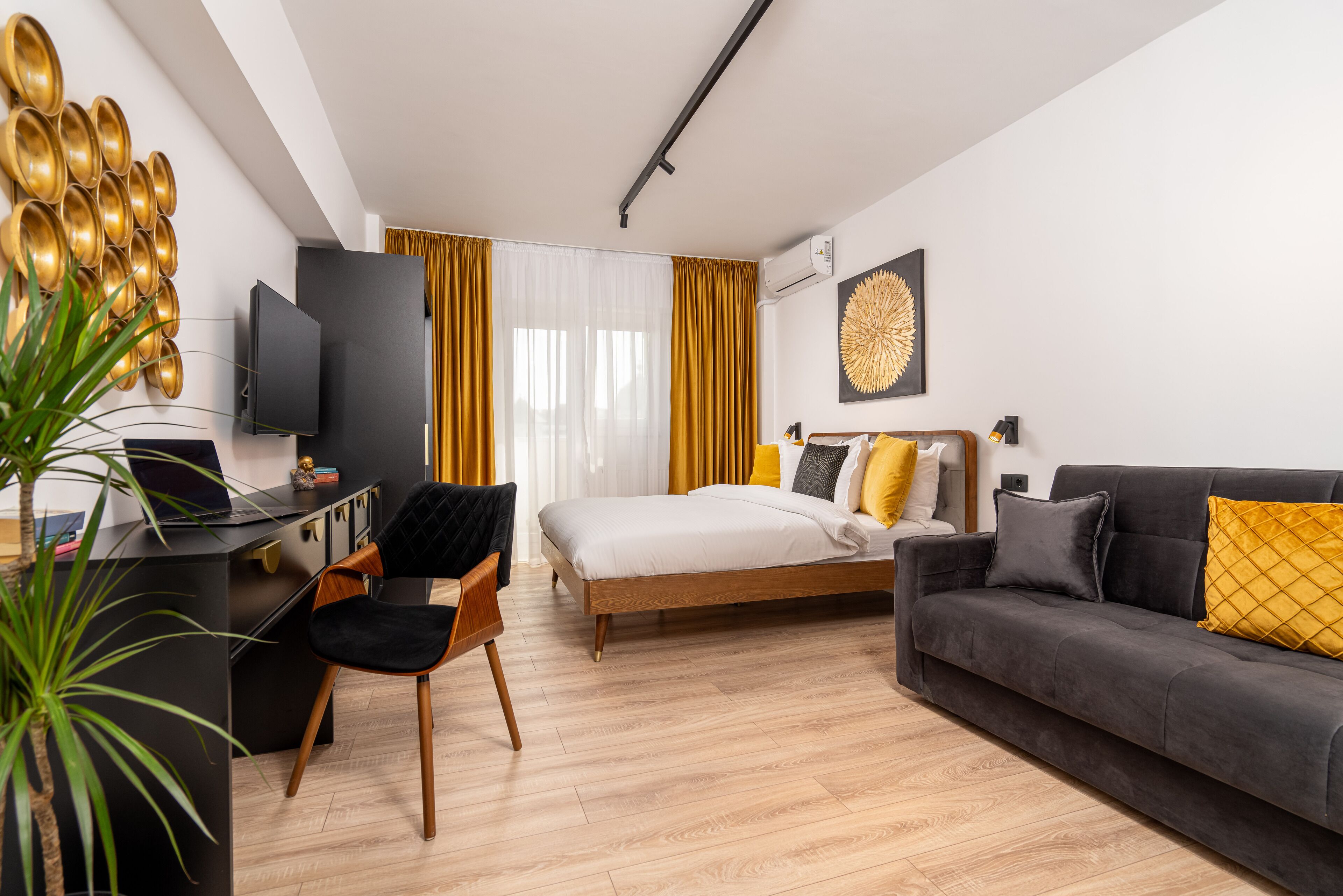 Habitación de hotel moderna con cama, sofá, escritorio y televisión.