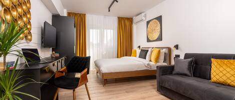 Habitación de hotel moderna con cama, sofá, escritorio y televisión.
