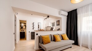 Ein modernes Wohnzimmer mit einer Couch, einem Essbereich und einer Küche im Hintergrund.