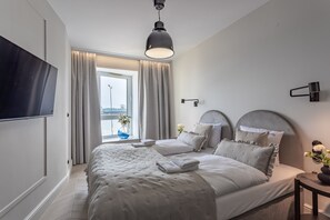 Een moderne hotelkamer met een groot bed, een flatscreen televisie, een raam met gordijnen en uitzicht op de stad.