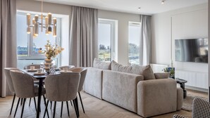 Un salon moderne comprenant un coin repas, de grandes fenêtres et un téléviseur à écran plat.