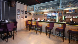 Una zona de bar con taburetes altos, una barra con menú de bebidas y un panel de malla azul.