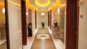 Un pasillo de hotel con suelo de baldosas, puertas de madera y un candelabro en el centro.