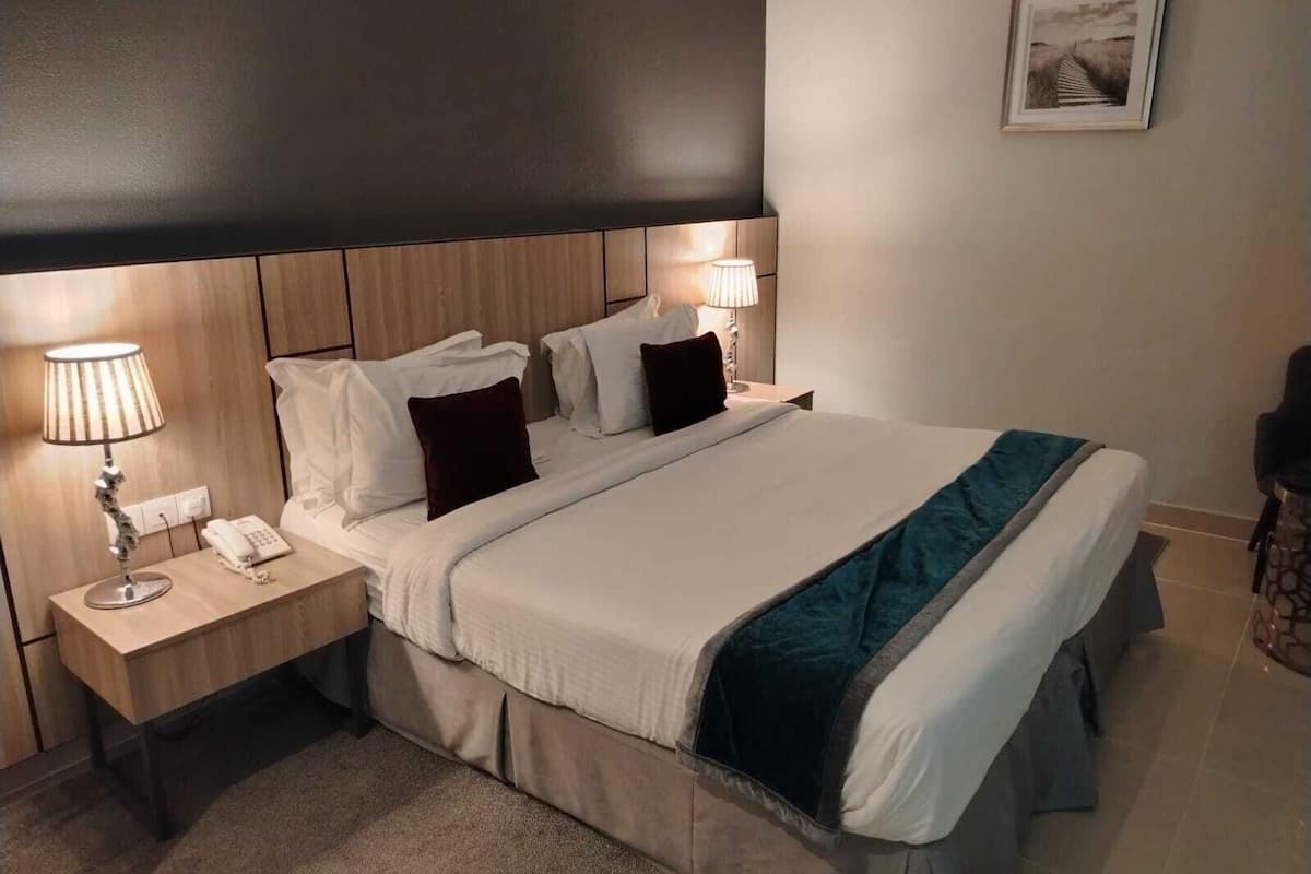 A neatly arranged hotel room with a bed, bedside tables, lamps, and a framed picture on the wall.