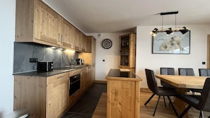 Eine moderne Küche mit Holzausstattung, einer schwarzen Arbeitsplatte und einem Essbereich mit Holztisch und -stühlen.