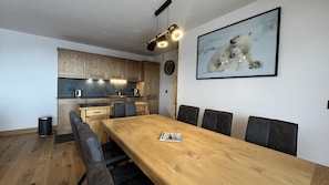 Eine moderne Küche mit Holzausbau, einem Esstisch mit sechs Stühlen und einem gerahmten Bild von Eisbären an der Wand.