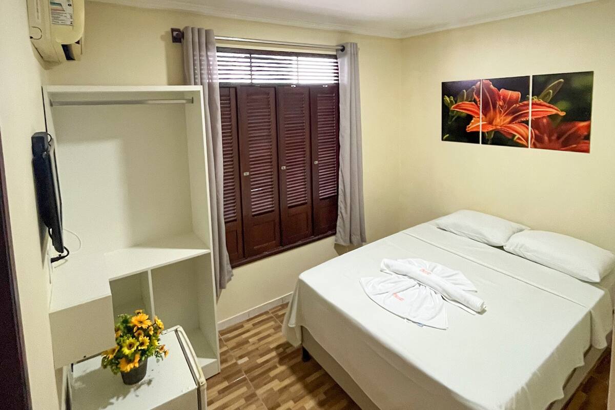 Ein Hotelzimmer mit einem Bett, einem Kleiderschrank, einem kleinen Schreibtisch mit Telefon und einem Fenster mit Vorhängen.